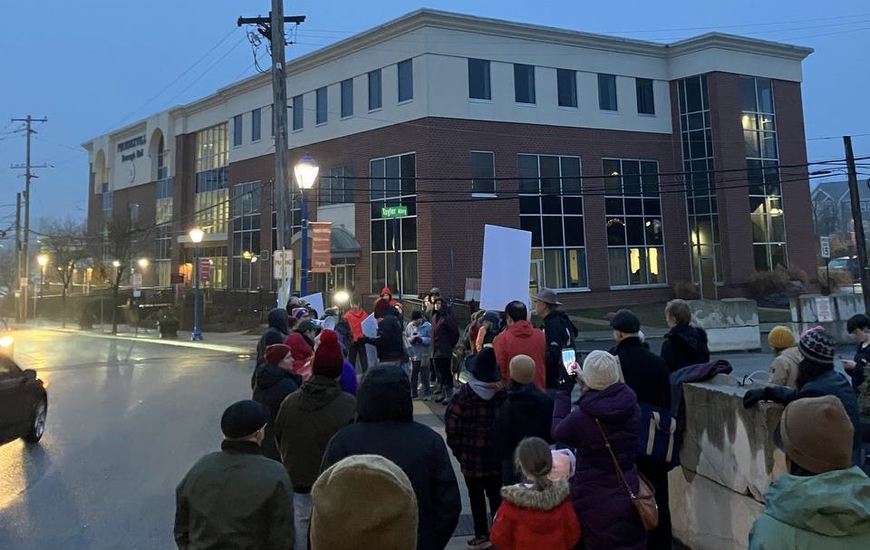 Singers and protesters gather outside the Borough Phoenixville on a cold, dark winter evening.